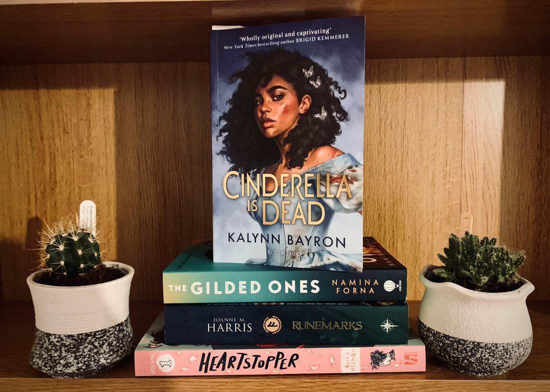 A stack of books including; Cinderella is Dead by Kalynn Bayron, The Gilded Ones by Namina Forna, Runemarks by Joanne M. Harris and Heartstopper Volume 1 by Alice Oseman